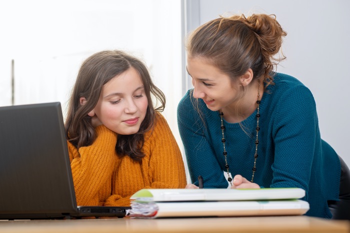 młoda korepetytorka pomaga nastolatce w pracy domowej - korepetycje
