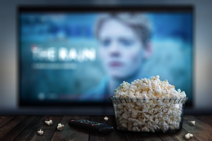 netflix serial rain - zamglony tv z popcornem i pilotem na pierwszym planie
